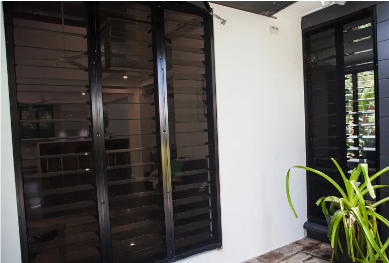 Black louvre windows with fly screens on a Darwin home exterior